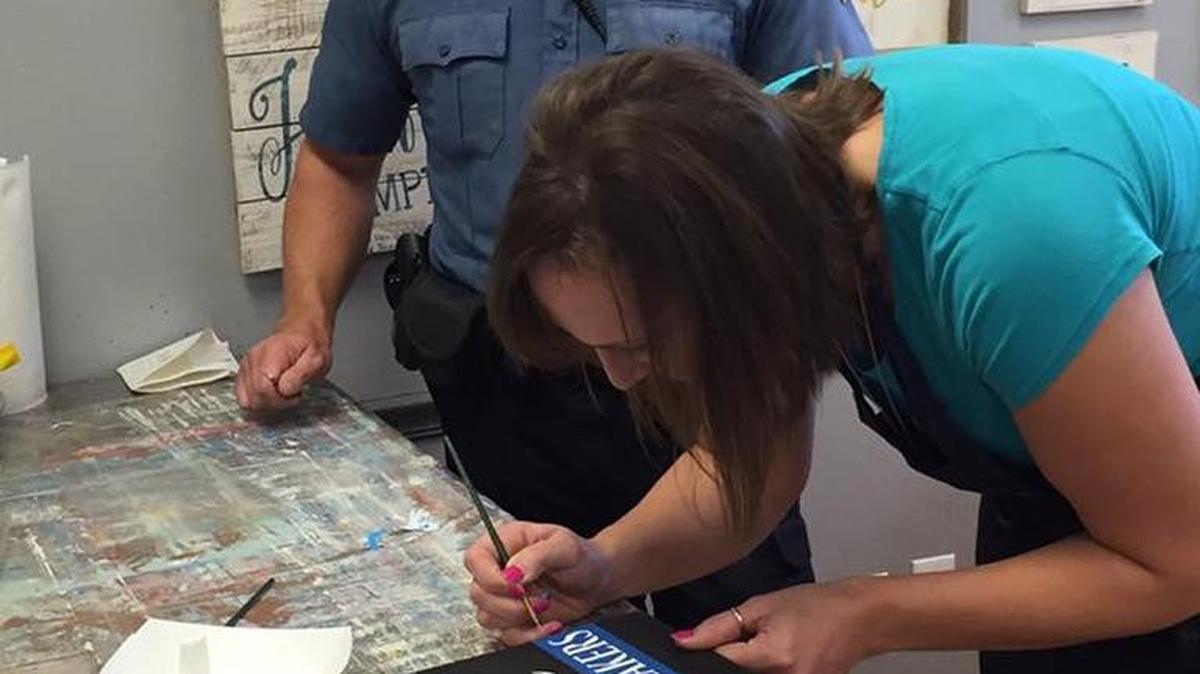 OPD Ofc. Clay Hoff looks on while C&G co-owner Lori Lambeth helps out with the details. The O'Fallon Police Department ‘Cops & Kids’ program (Christmas fund) fundraiser today at Courage & Grace art studio on the 15th anniversary of the 9/11 event that shook our country.