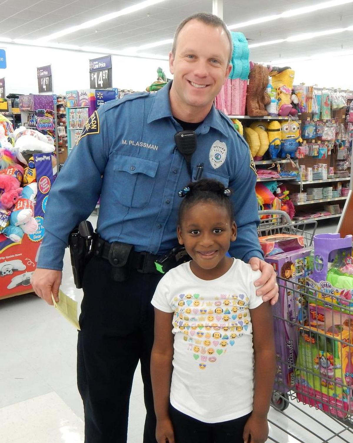 Officer Matt Plassman with Myah, 6, during OPD’s Christmastime Cops and Kids event at Walmart.