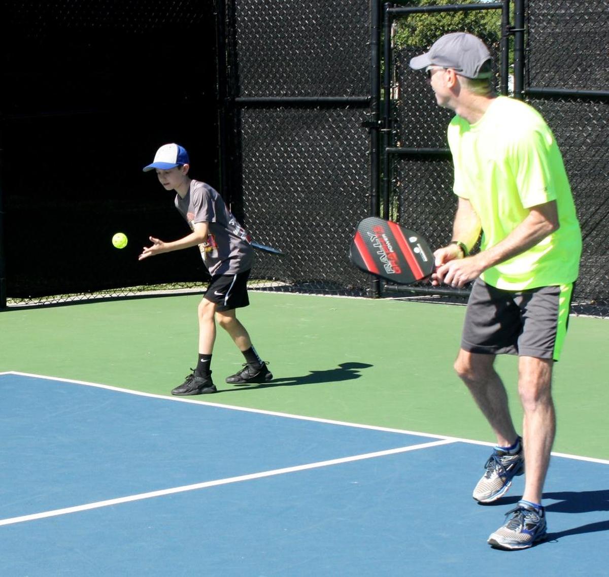 In this BND file photo, Jack Tredway, 12, serves while his father Trevor Tredway looks on during a doubles pickle ball match in 2017 at Hesse Park in O’Fallon. Plans to expand pickleball courts in O’Fallon beyond four will have to wait until the budget allows but resurfacing and revising the current court direction is still on track.