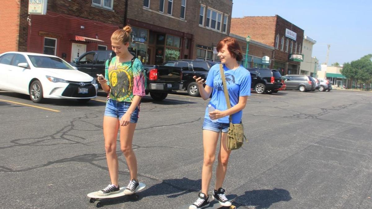 Playing Pokémon GO in O’Fallon...Mackenzie Clubb and Ashleigh Rowe of O’Fallon skateboard through downtown O’Fallon Tuesday, playing Pokémon GO. This new phone app allows players to capture, battle, and train virtual Pokémon who appear throughout the real world, including numerous spots in O’Fallon. Rowe, who started to play the game on Monday, said she had already captured 26 Pokémon as of early Tuesday morning. Meanwhile, Clubb started to play on July 13. She said she has captured 64 Pokémonm including some by the caboose in downtown O’Fallon and the O’Fallon History Museum. “It’s cool,” Clubb said about the app, which was was initially released in July for iOS and Android devices, starting with the U.S. and Australia, with Asian, and European releases to follow. The game has received a mixed critical reception. However, it was the most downloaded smartphone app in the US in its first three days of release and has been a boon to publisher Nintendo's stock value.