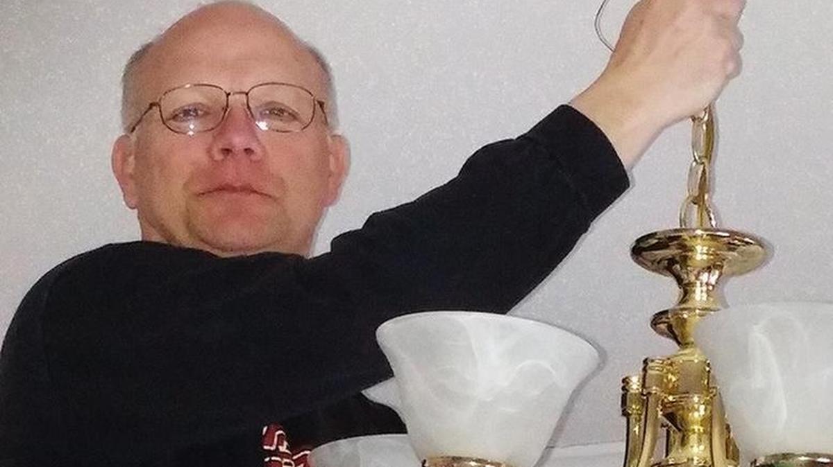Dwight Dettmann, founder of Bright Ideas & More, LLC, installs a light fixture.