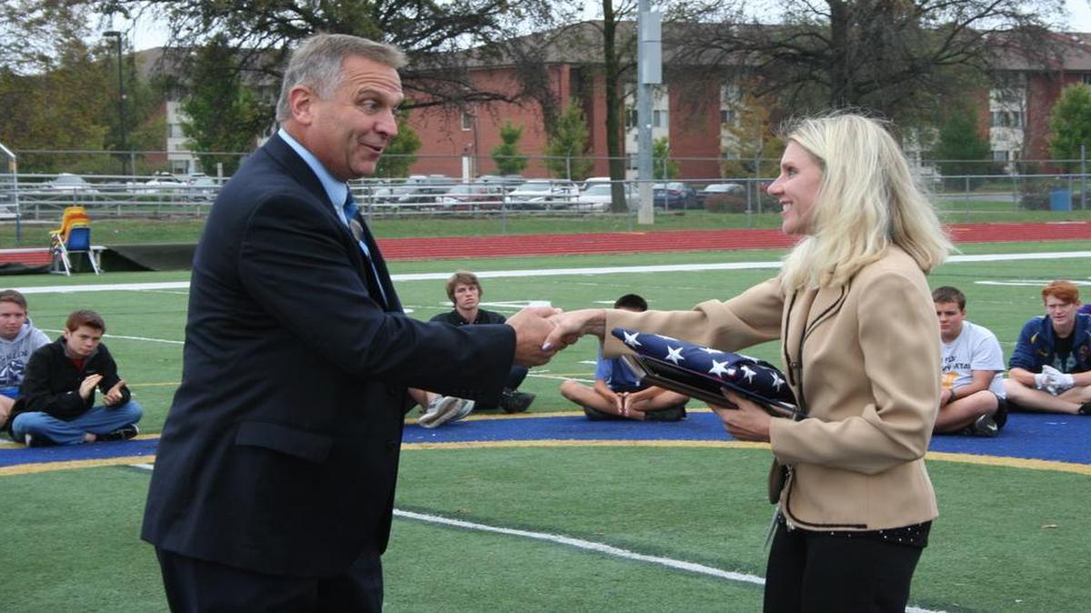 Congressman Mike Bost presents a plaque and flag to O’Fallon Marching Band Director Melissa Gustafson-Hinds.