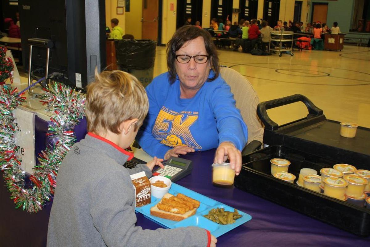 O’Fallon School District 90 Estelle Kampmeyer Elementary kindergarten and third-grader students take turns waiting in line with Robin Stone, cashier of 15 years with Sodexo.