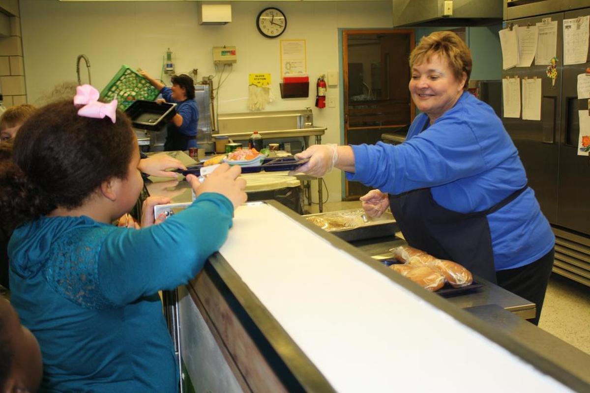Judy Shannon, a 15-year veteran worker with Sodexo, hands a student her lunch tray at O’Fallon School District 90 Estelle Kampmeyer Elementary.