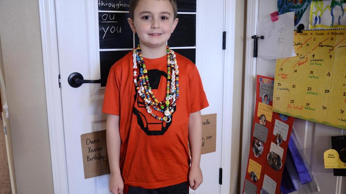 Owen Clive, 8, cancer survivor who’s been in remission for three years and counting shows off his ‘beads of courage.’
