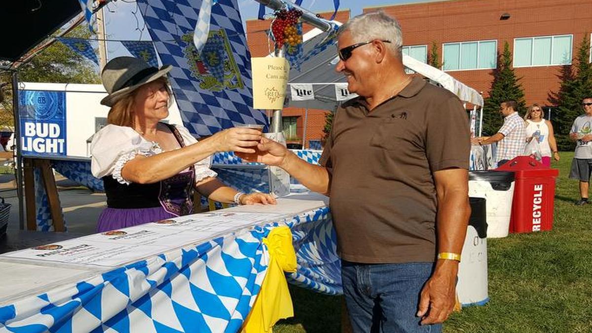 Kathy Sjoquist, sporting a German costume, serves a beer to Jim Deschesne during the Oktoberfest at St. Clare Catholic Church in O’Fallon.