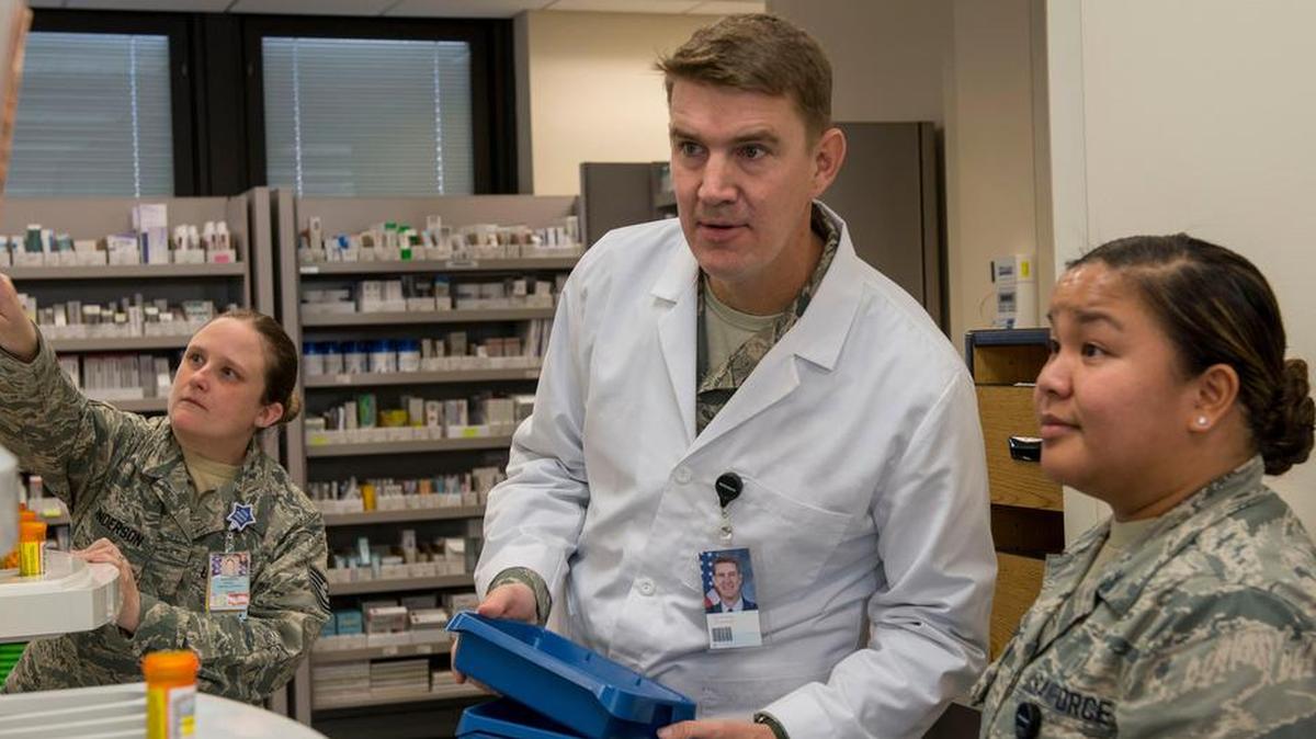 Senior Airman Andrea Aquino, (right), and Tech. Sgt. Anna Anderson, 375th Medical Support Squadron pharmacy technicians, show Col. John Howard, 375th Air Mobility Wing commander, how to check pharmacy records Nov. 27. Howard filled prescriptions while Chief Master Sgt. Patricia Hickey, 375th AMW command chief, handed out medications to patients at the front desk.