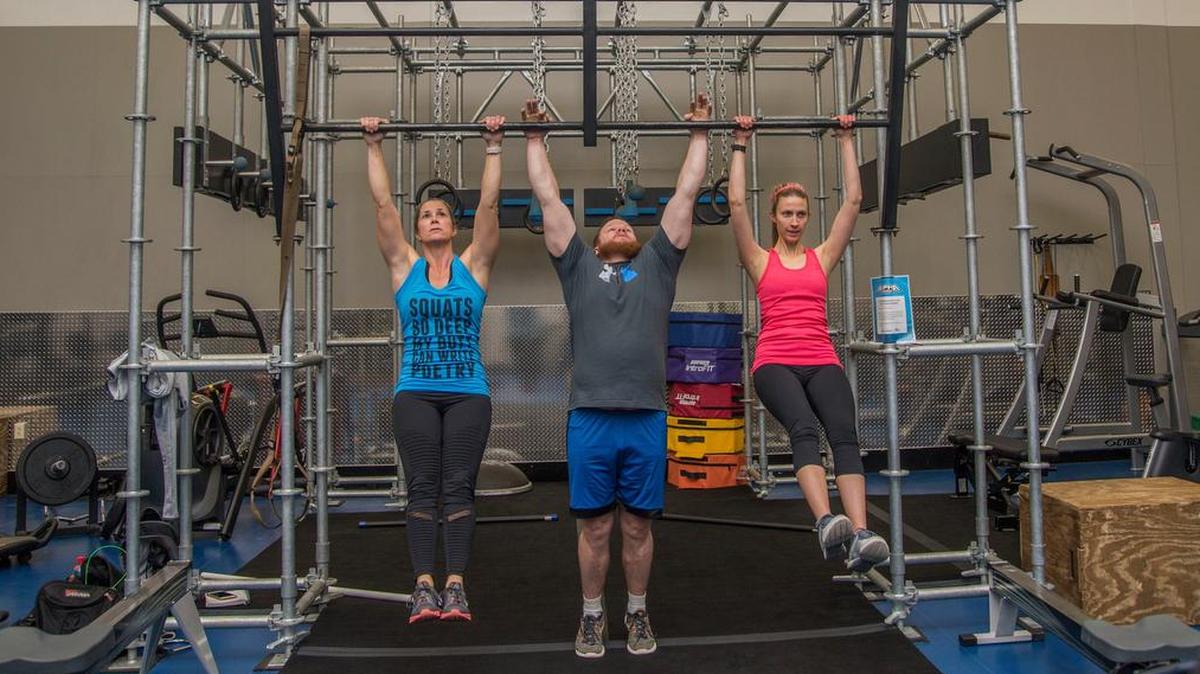 Stefanie Tucker, Steven Tucker, and Jamie Knight perform pull-ups on the newly installed Alpha Warrior Battle Rig at Scott. In addition to location renovations, the 375th FSS expanded the services they provide to the base, such as adding the battle rig to the base gym.