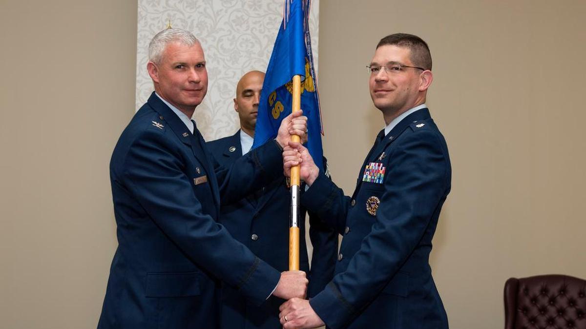 Col. Marc Packler, 375th Communications Group commander, presents the 375th Communications Squadron guidon to Lt. Col. Frank Theising during a change of command ceremony July 3 at Scott Air Force Base. Theising assumes command from Lt. Col. Jason Parker.