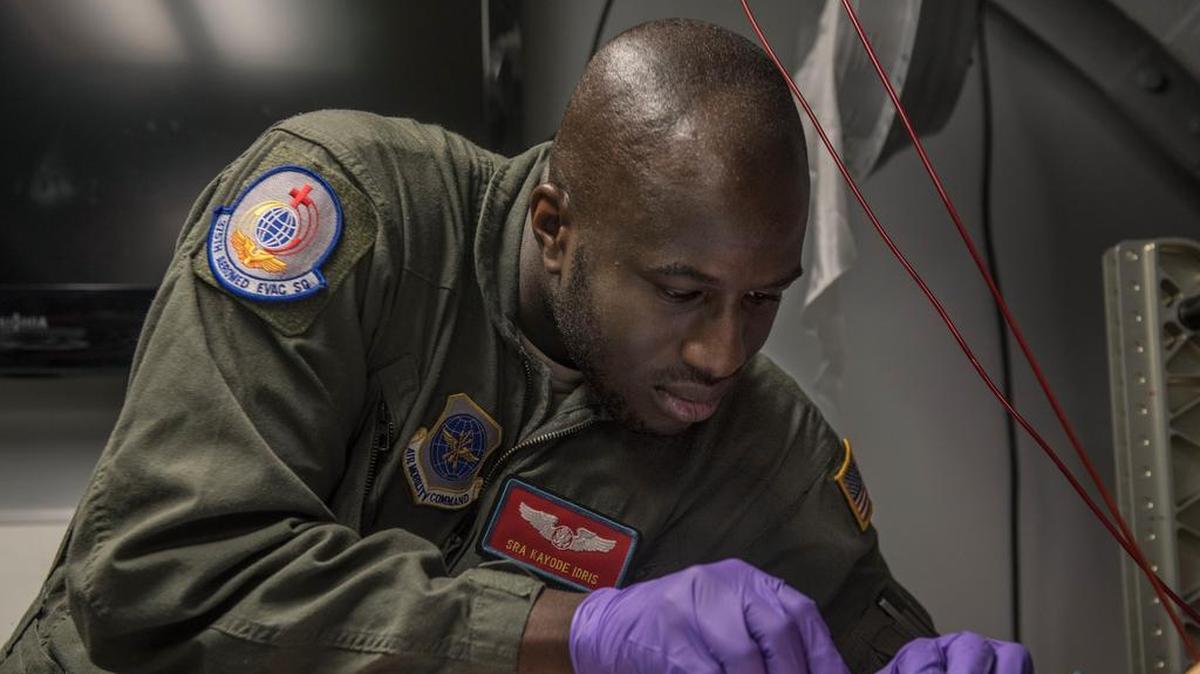 Senior Airman Kayode Idris, 375th Aeromedical Evacuation Squadron, prepares an IV for a simulated patient on the cargo compartment trainer.