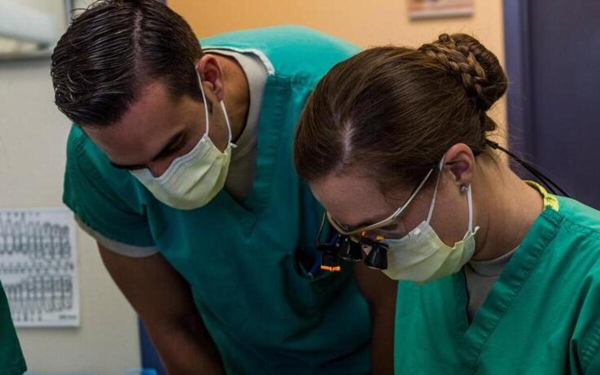 Maj. David Servello, chief of orthodontics, oversees the work of Capt. Rachael Sells as she conducts an operation giving a patient braces. Sells is one of four residents in the Advanced Education in General Dentistry Program.