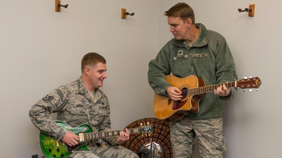 Staff Sgt. Andrew Norris, 375th Operations Support Squadron airfield systems technician, plays guitar with Col. John Howard, 375th Air Mobility Wing commander, during Take Your Commander to Work Day. Howard coined Norris for his impromptu performance during his tour of the Air Traffic Control Approach and Landing Systems building.