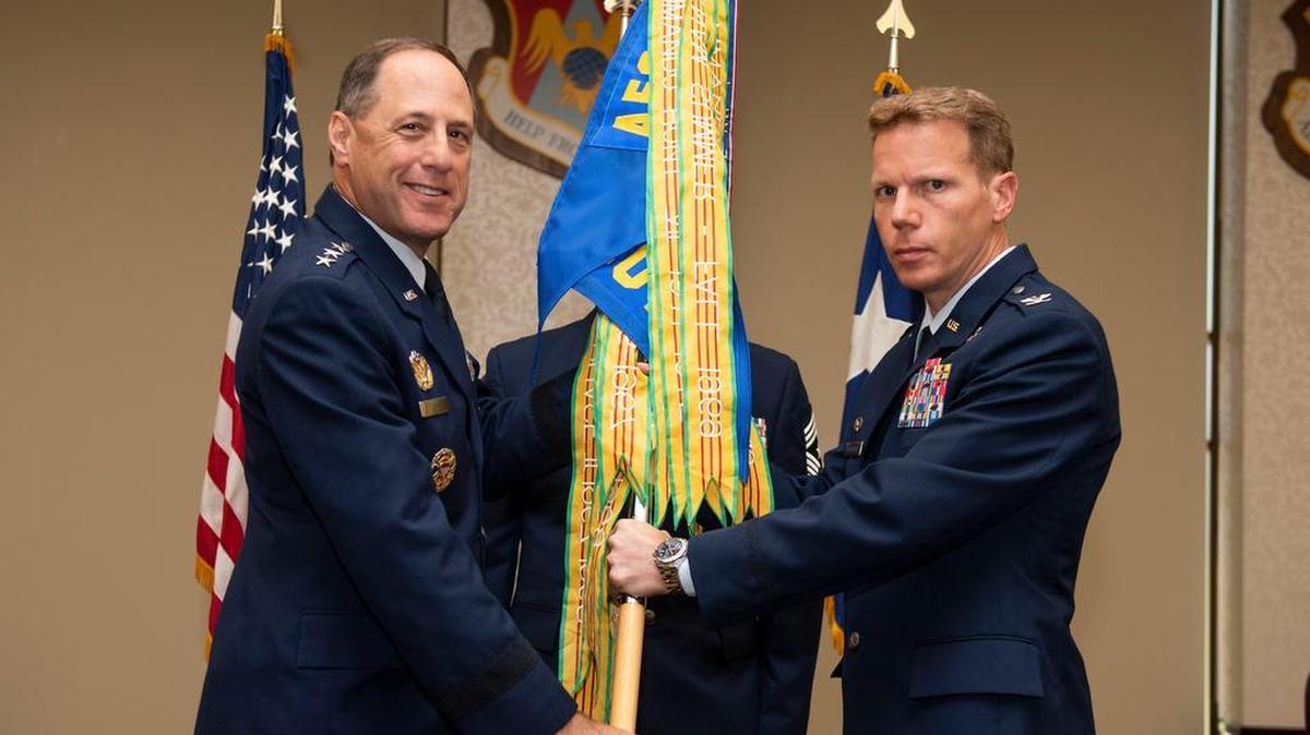 Lt. Gen. Lee Levy II, Air Force Sustainment Command commander, presents the 635th Supply Chain Operations Wing guidon to Col. Robert Henderson during a change of command ceremony July 20 at Scott Air Force Base. Henderson will take control of the only operational warfighting wing of the AFSC under Air Force Materiel Command. Photo by Airman 1st Class Tara Stetler