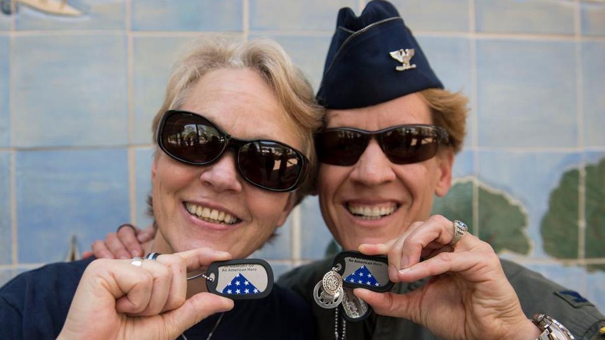 Cathy Berlin-Obregon, a Gold Star family member, and Col. Laurel Burkel, Air Mobility Command Fuel Efficiency Division chief, hold up their dog tags that honor Maj. Phyllis Pelky, Obregon’s late sister. Pelky was killed in a helicopter crash in 2015, and Obregon and Burkel have helped each other grieve her loss.