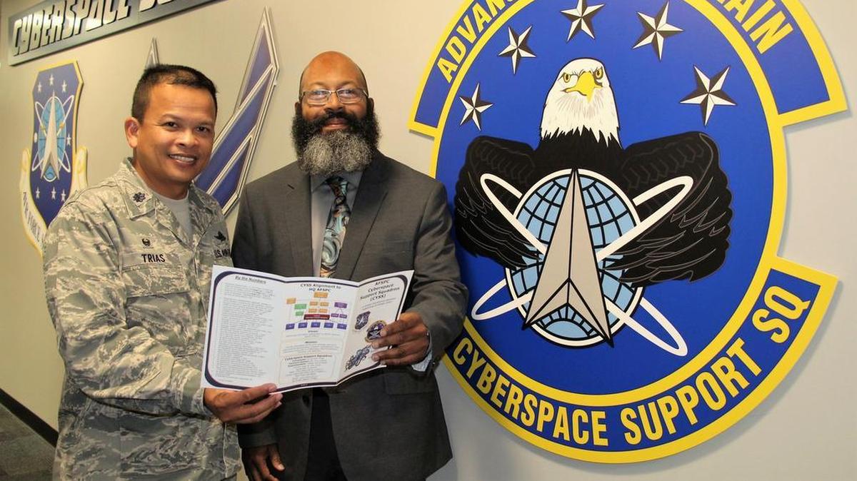 Lt. Col. Eric Trias, Cyberspace Support Squadron commander, and Joseph Mukes, system manager, review high frequency functions within the CYSS tri-fold.