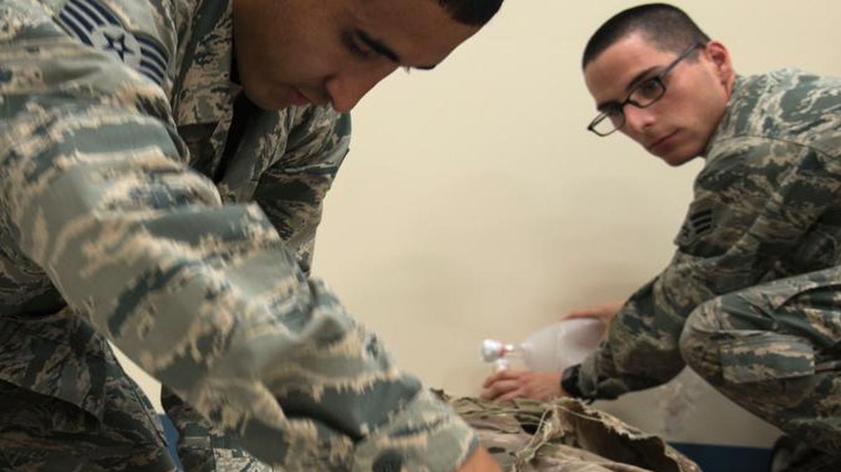 Senior Airman Chris Funn, 375th Medical Operations Squadron aerospace medical technician, performs assisted ventilation while Staff Sgt. Orlando Navarro, also an aerospace medical technician with the 375th MOS, applies a pressure bandage to a simulated blast patient while training for the Emergency Medical Technician Rodeo.