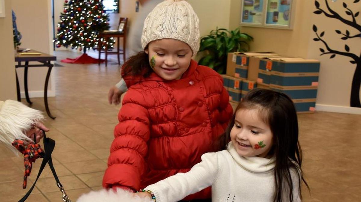 Esli and Emy Amaya pet Obie, a service dog owned by Maj. Erica Salerno, USTRANSCOM, during the USTRANSCOM Children’s Holiday party Dec. 3 in the Lincoln’s Landing Community Center. The youngsters were treated to games, crafts and refreshments as they awaited the arrival of Santa, who gave all the children gifts.
