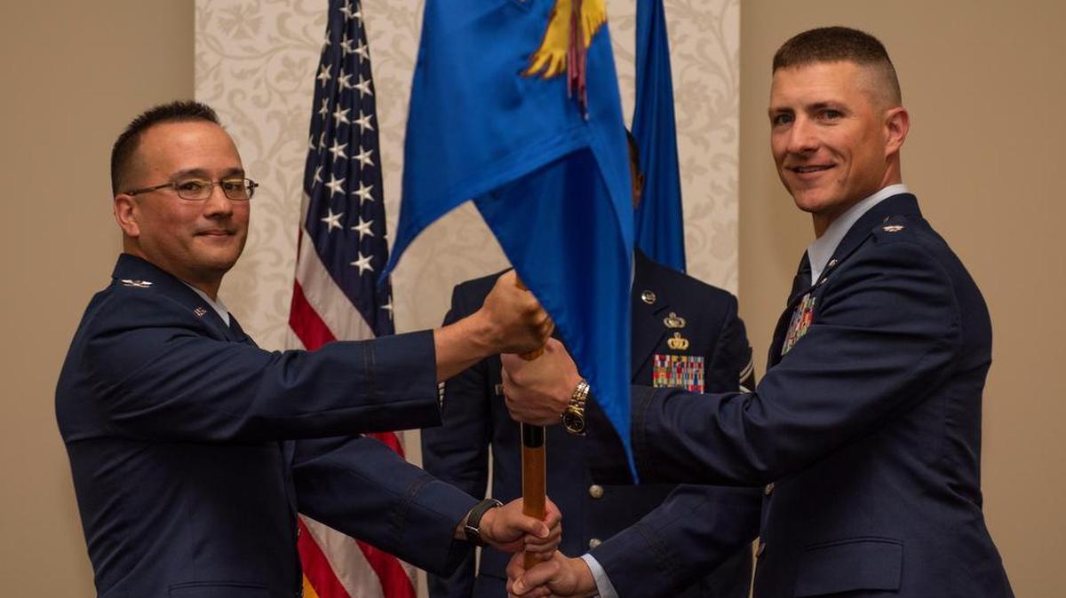 Col. Andrew Torelli, Air Mobility Command Director of Intelligence, Surveillance and Reconnaissance, presents the Air Mobility Command Air Intelligence Squadron guidon to Lt. Col. Douglas Mabry during a change of command ceremony June 28 at Scott Air Force Base.