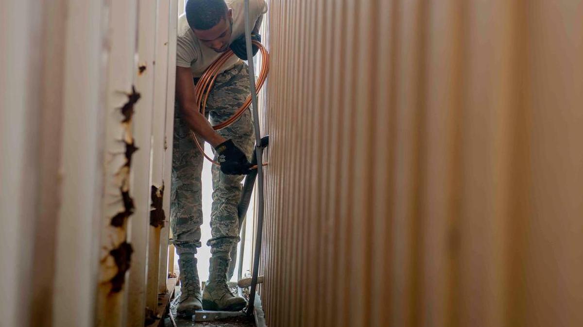 Airman 1st Class Joshua Allen, 375th Civil Engineer Squadron HVAC technician, feeds a discharge line through the wall during an air conditioner installation, Sept. 24 at Scott Air Force Base. This line discharges refrigerant to the condenser, which fans it to remove heat. Photo by Airman 1st Class Tara Stetler