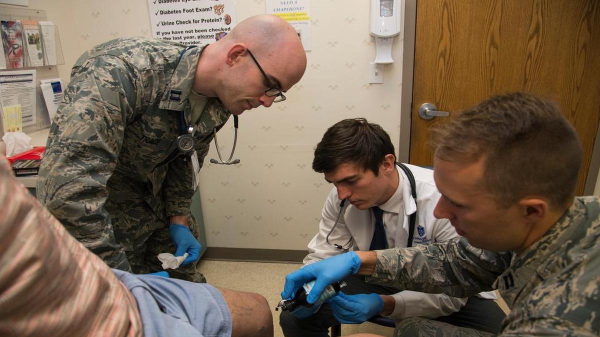 Scott Flewellyn (middle), medical student, inserts a vaccination into a patient’s knee. Capt. Dylan Tracy (left), Family Medicine Residency student, observes the injection, while Capt. Trevor Smith (right), faculty member, guides the process and mentors the students. The residency program is one in which residents work with patients and are able to be guided and mentored by experienced faculty members.