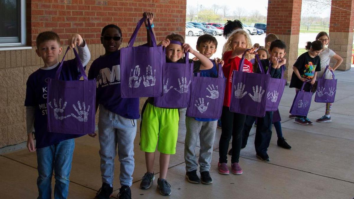 Scott Elementary School second graders stand in line with their newly painted recyclable bags. One person using reusable bags over their lifetime would remove more than 22,000 plastic bags from the environment.