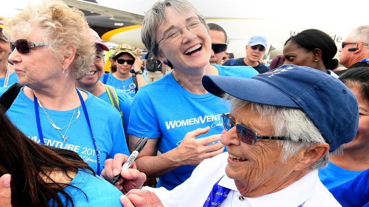 Secretary of the Air Force Heather Wilson laughs with Women’s Auxiliary Service Pilot Jane Doyle while she autographs a T-shirt following a group portrait of women aviators in Oshkosh, Wis.