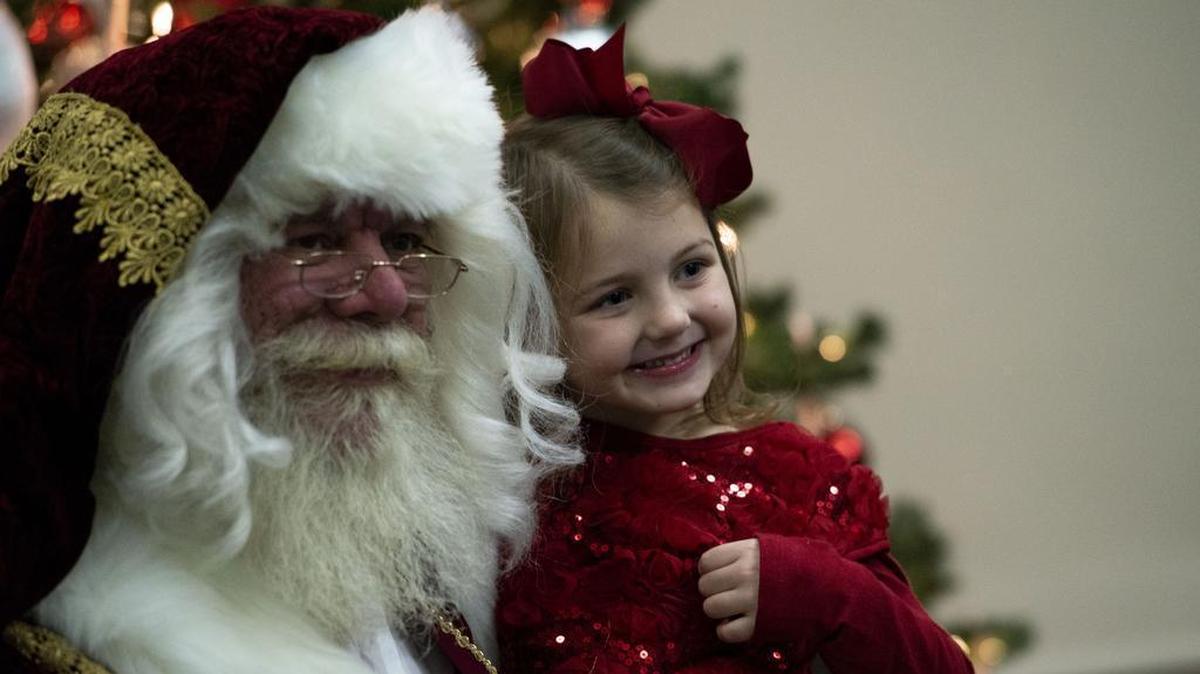 Santa and a young member of Team Scott sit for a photo during the Holiday Party and Tree Lighting Ceremony on Dec. 7 at Scott Air Force Base. During the event, the non-profit organization Trees for Troops provided free Christmas trees to families around base, ensuring all young Airmen and families of deployed service members could decorate for the holidays. Photo by Senior Airman Tara Stetler