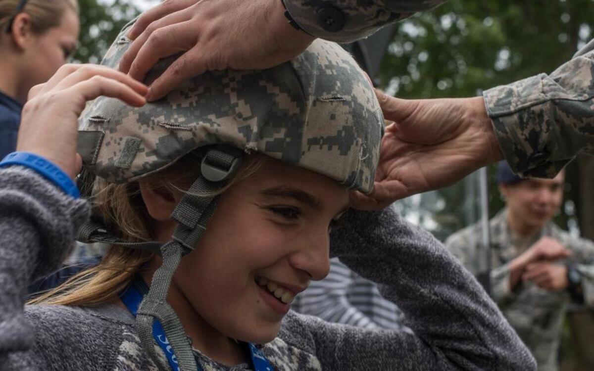 A 375th Security Forces member helps McKenzy Gleadle, an eighth grade Central Middle School student, put on a helmet during a security forces demonstration.