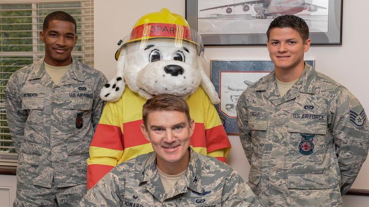 Col. John Howard, 375th Air Mobility Wing commander, signs a proclamation for Fire Prevention Week. Pictured behind Howard are Senior Airman Darnell Bowden, 375th Civil Engineer Squadron firefighter; Sparky the Fire Dog; and Staff Sgt. Keith Engle, 375th CES fire inspector.