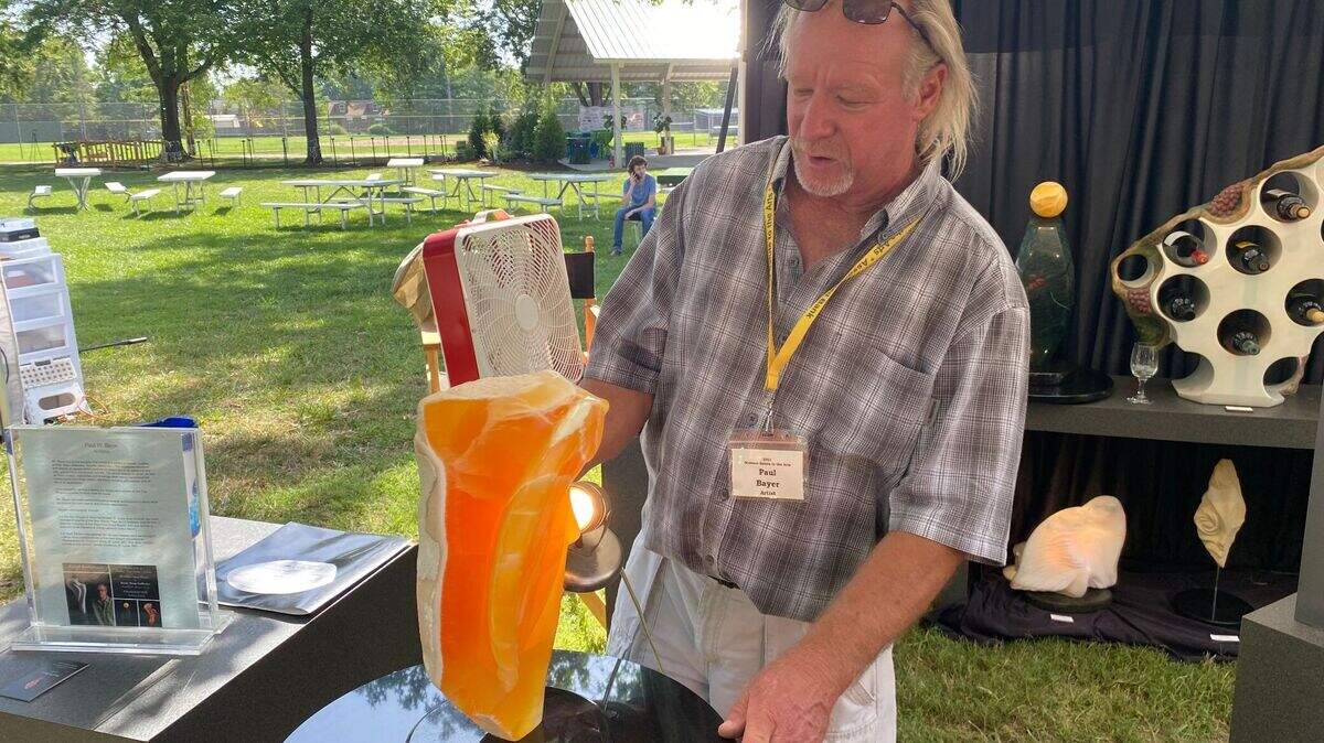 Paul W. Bauer, a sculptor from St. Louis, uses a light to show the translucency of “Lioness,” one of his sculptures made of honeycomb calcite. Bauer said he has been coming to the annual Midwest Salute to the Arts festival in Fairview Heights for many years.