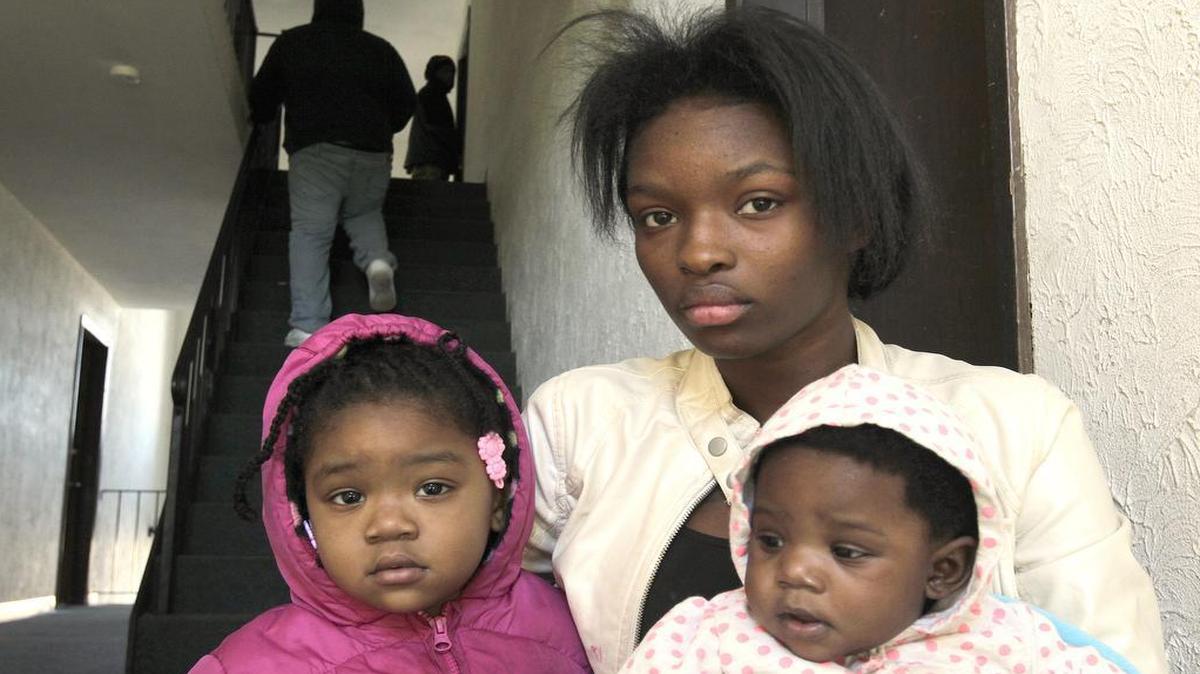 Jasmine Lott, a friend of the shooting victim, holds his two small children inside the apartment complex where he lived. Carl Silas was shot and killed early Friday morning inside his apartment at 2913 West Boulevard in Belleville. At left is 2-year-old Gionna Silas, and at right her sister, four-month old Ivyonna Silas.