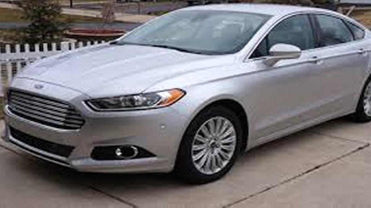 The squad car is a 2014 Silver Ford Fusion, with no visible police markings or lights. It has an Illinois license plate, B372394.