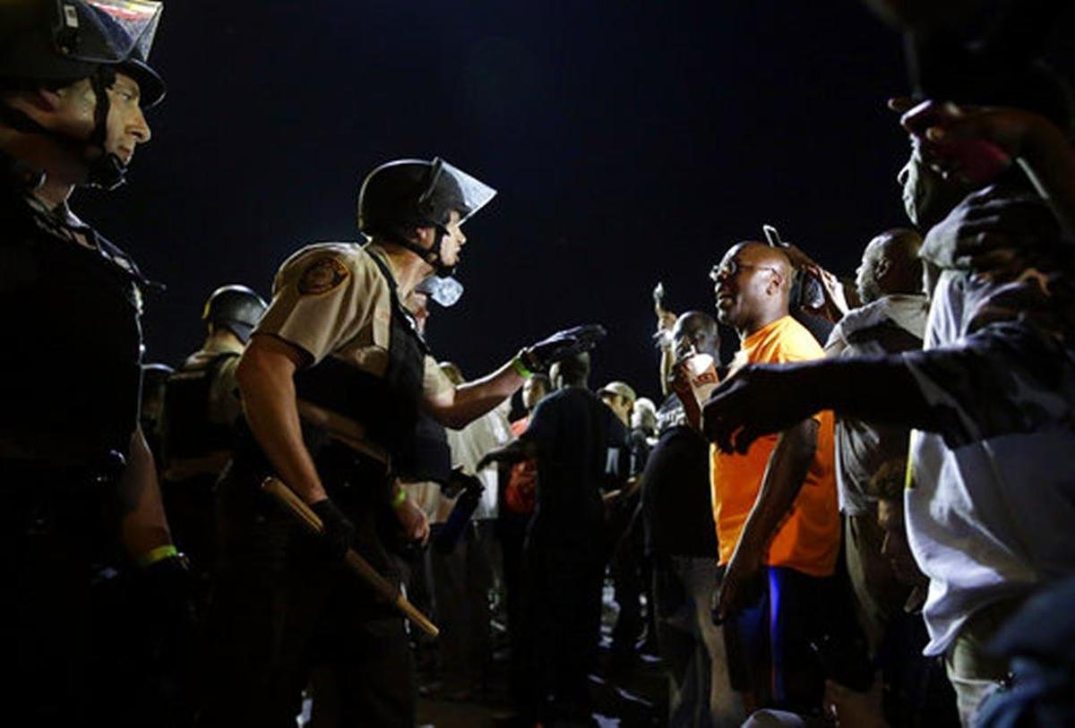In this Aug. 10, 2015, file photo, officers and protesters face off along West Florissant Avenue, in Ferguson, Missouri. A federal judge will get an update Tuesday, Dec. 12, 2017, on progress the city of Ferguson is making in addressing concerns about mistreatment of black residents by the Missouri town’s police and court system.