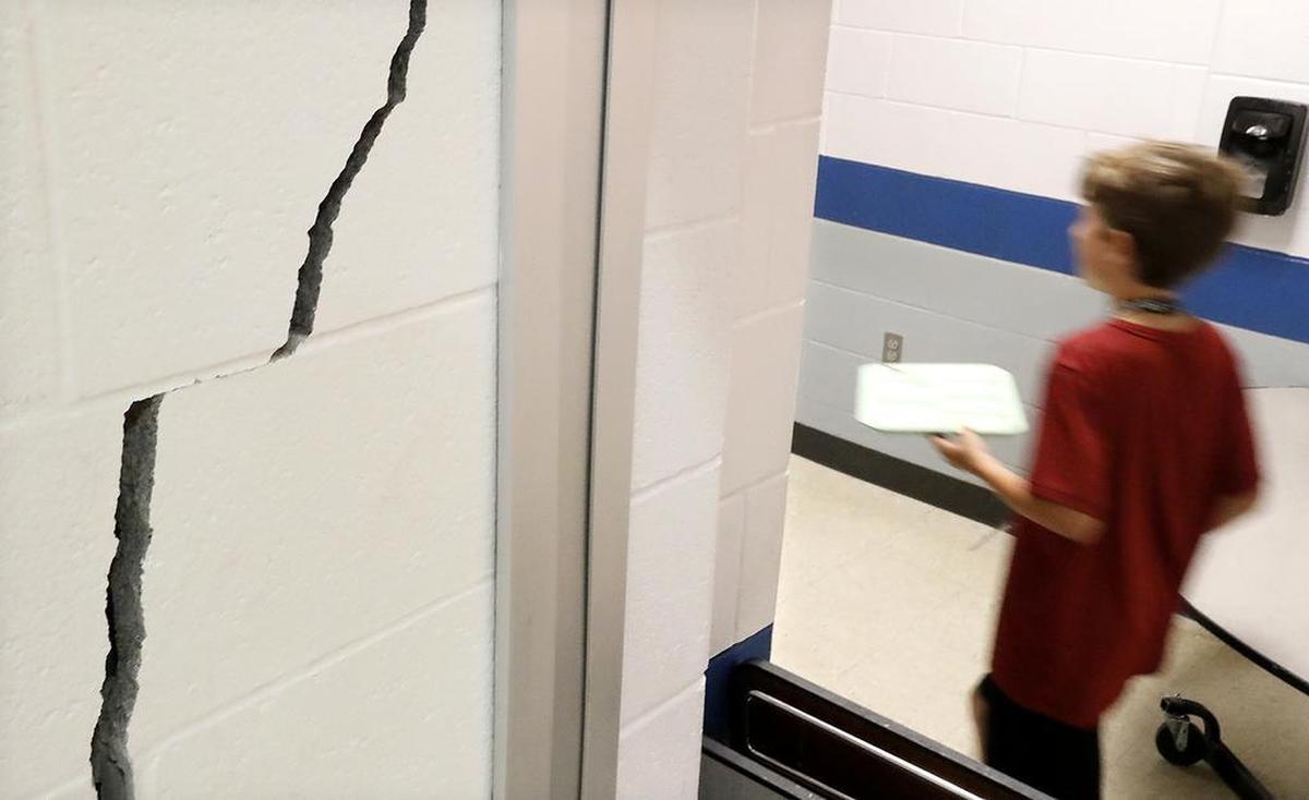 A student walks by a one-inch wide crack which is several feet high Monday at Wolf Branch Middle School in Swansea.