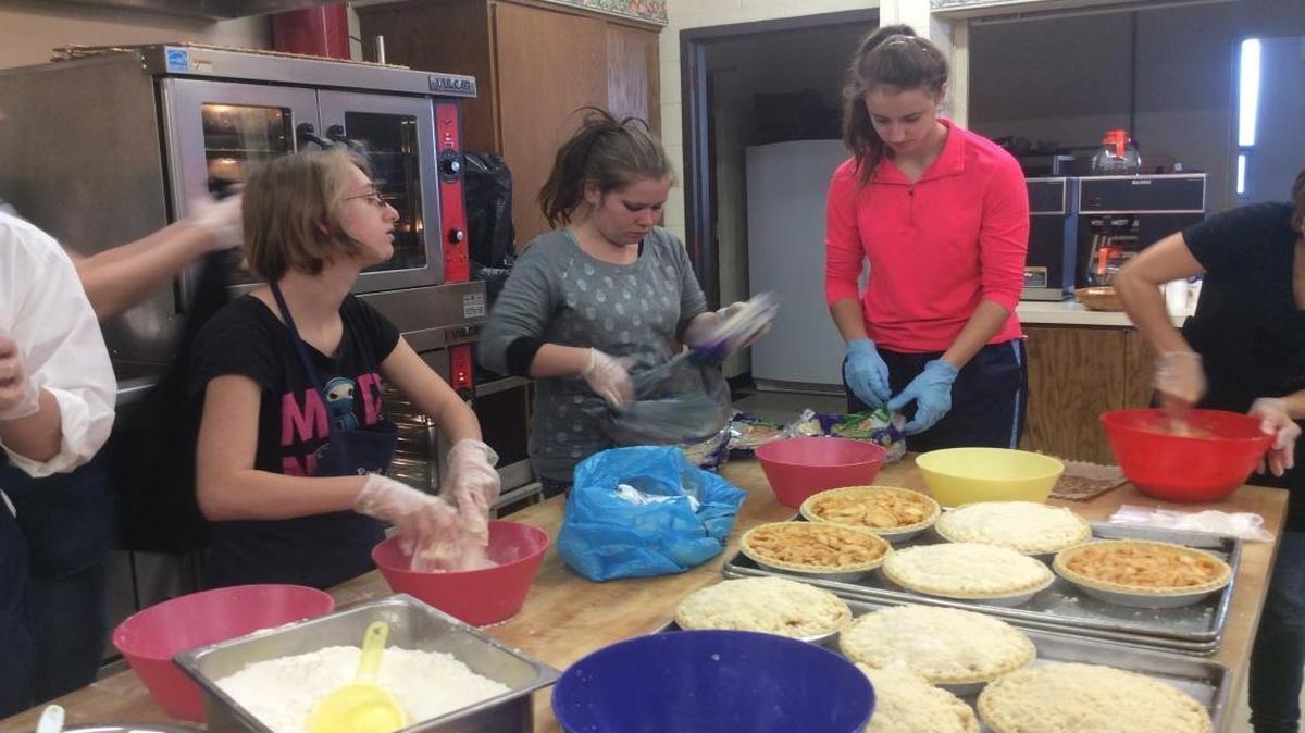 Amanda Slagle, left, makes crumb topping for the 42 apple crumb pies while Melissa Powell and Danielle Mongeon unwrap pie crust.