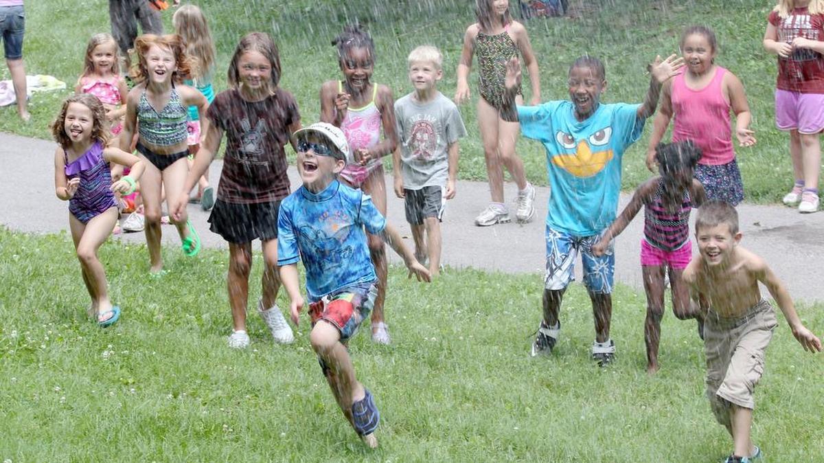 Members of the Belleville Fire Department help cool down children at Camp Quackers in Bellevue Park.