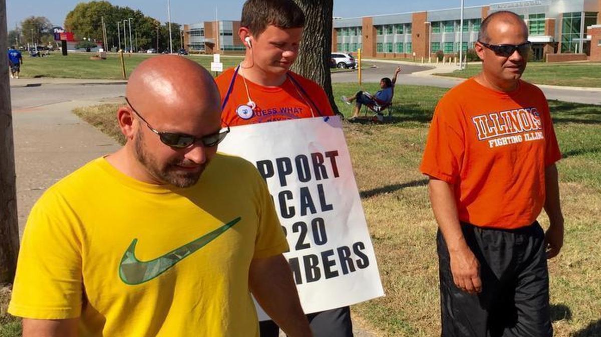 Striking East St. Louis teachers Jeff Schneider, Josh Cummins and Paul Thies on Wednesday walk the picket line in front of East St. Louis Senior High School.