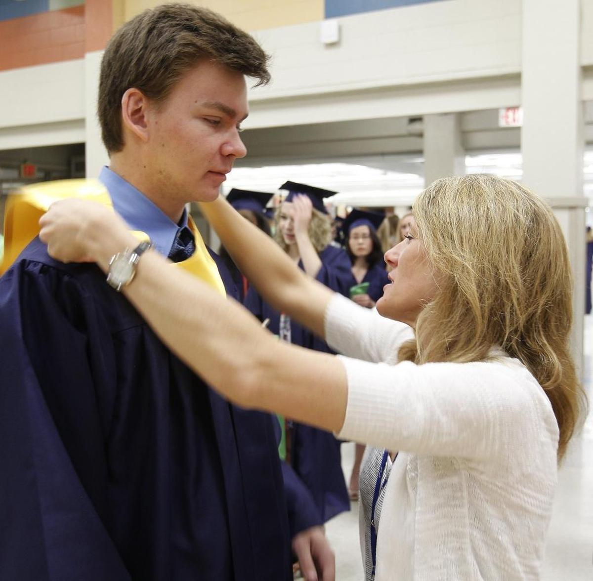 Jackie Maxwell, at right, places a National Honor Society stole around the neck of a May 2017 O’Fallon Township High School graduate.