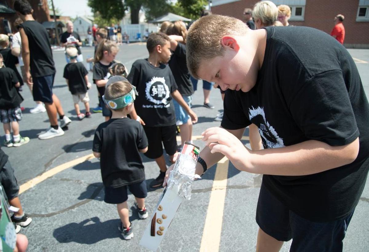 St. James student Jeremy Scheibel looks at the shadow of the sun with a pinhole viewer during the solar eclipse in Millstadt on Monday. Jeremy also celebrated his birthday on Monday.