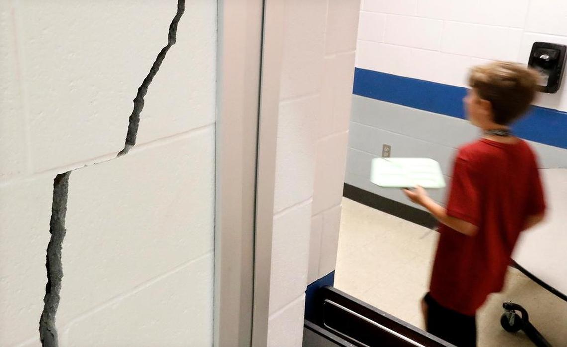 A student walks by a one-inch-wide crack that is several feet high Monday at Wolf Branch Middle School in Swansea.