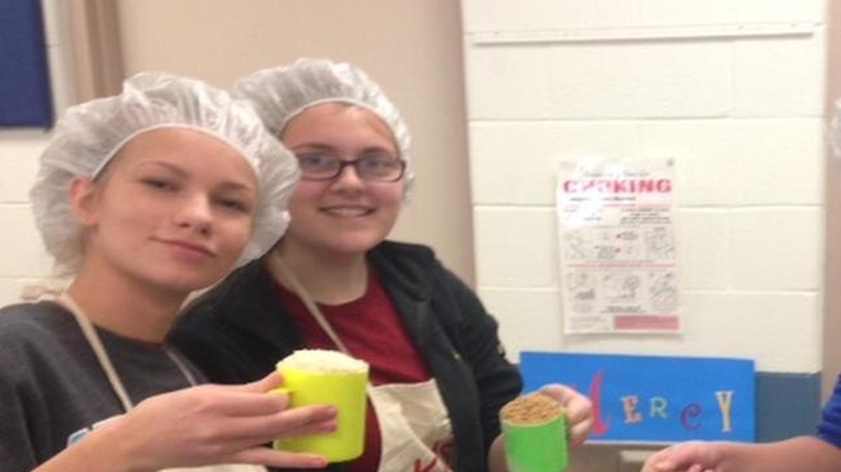 Builders Club members Claire Huebner, left, Hannah Janson, Nick Prindiville and Katrina Costner scoop ingredients for Kids Against Hunger. The Builders Club members are seventh and eighth graders at Immaculate Conception School.