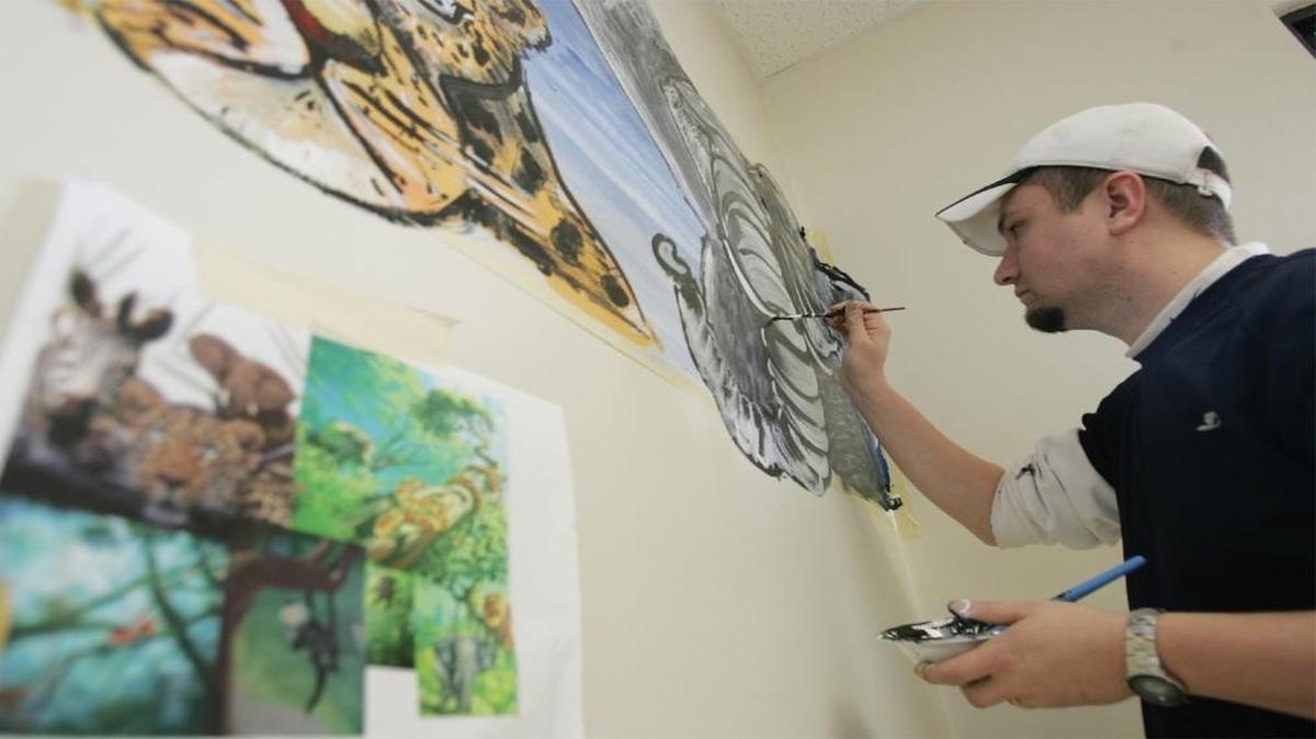 In this 2006 file photo, former High Mount Elementary School art teacher George Wilkerson works on a mural inside Swansea’s demonstration library. Wilkerson will return to High Mount next year as its new principal.