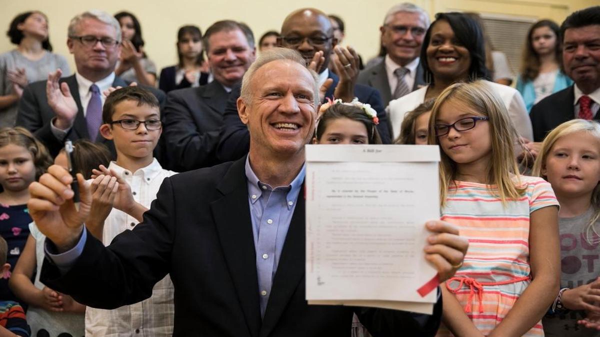 In this Aug. 31, 2017, file photo, Illinois Gov. Bruce Rauner signs education funding reform bill SB 1947 at Ebinger Elementary School in Chicago. Democratic-leaning Illinois is the latest state to direct taxpayer money to private schools, a move that’s caught some by surprise and drawn condemnation from politically powerful teacher unions and Democrats looking to defeat Republican Gov. Rauner in 2018.