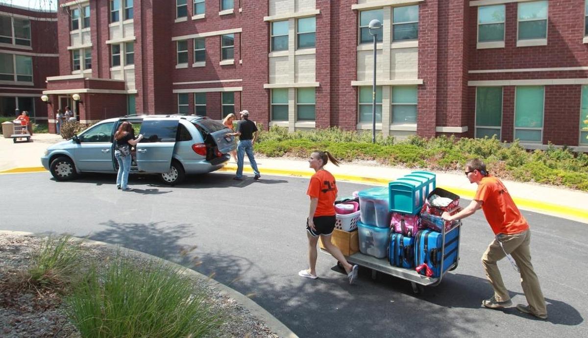 In this August 2014 file photo, Southern Illinois University Edwardsville students push a cart full of items for an incoming freshman to Woodland Hall, one of the dorms on campus.