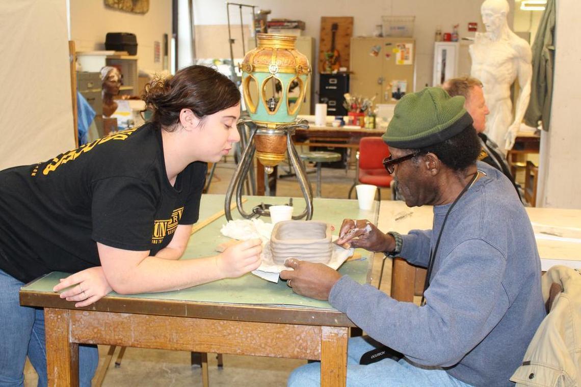 Volunteer Amanda Bushey, left, of Fenton, Missouri, helps veteran James Howard, of Alton, who is legally blind, make a ceramic casserole dish in the sculpture studio at Fontbonne University as part of the Visions for Vets art program.