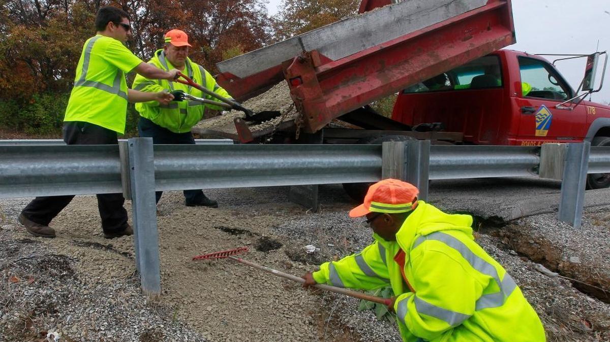 St. Clair County highway workers put a rock-fill mix into a washout along Frank Scott Parkway, then tamped in cold-patch over it to prevent future erosion.