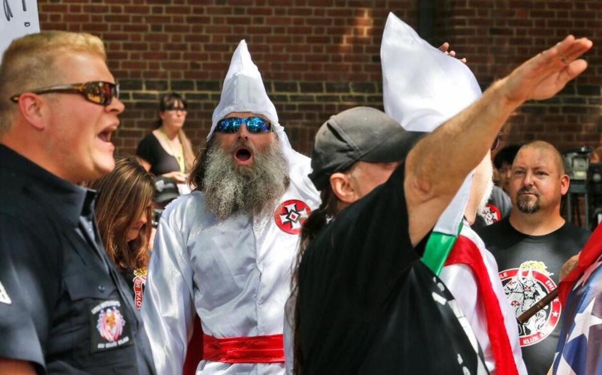 Members of the KKK are escorted by police past a large group of protesters during a KKK rally Saturday, July 8, 2017, in Charlottesville, Va.