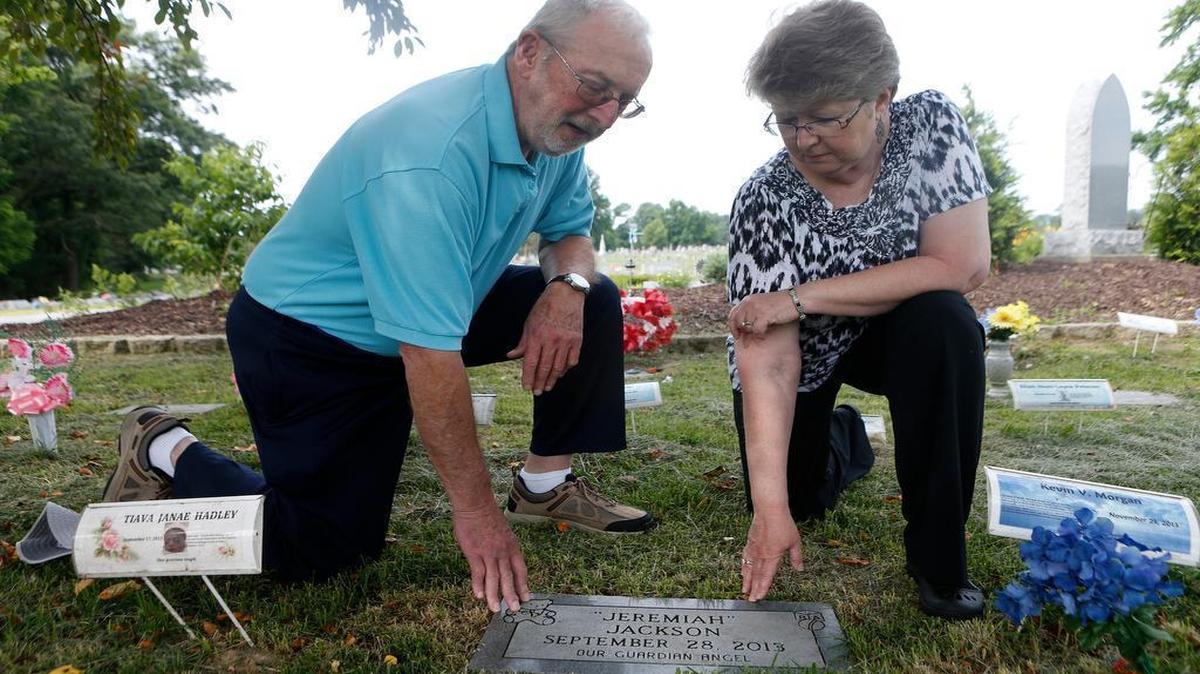 
Father Clyde Grogan and Mount Carmel Cemetery office manager Dee Dee Murray pray at Jeremiah Jackson's grave on Thursday morning.
