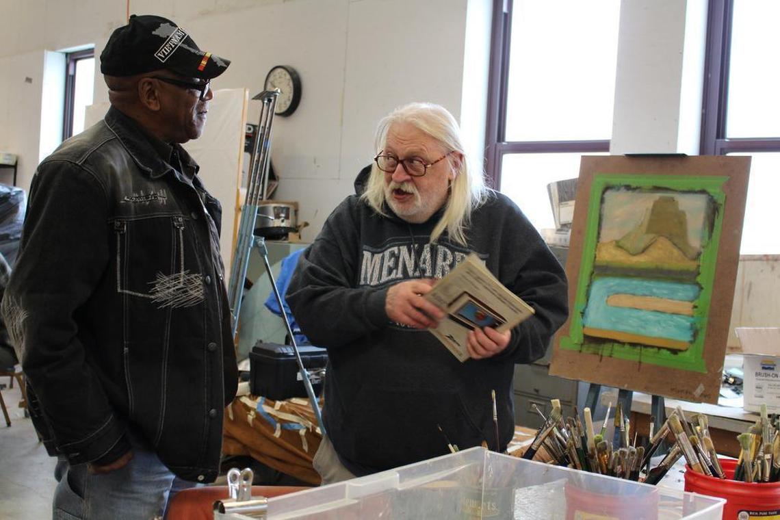 Bob Wunderlich, right, of St. Louis, tells fellow veteran Del Marion, of East St. Louis, about a National Geographic photo that inspired his painting in the sculpture studio at Fontbonne University as part of the Visions for Vets art program.