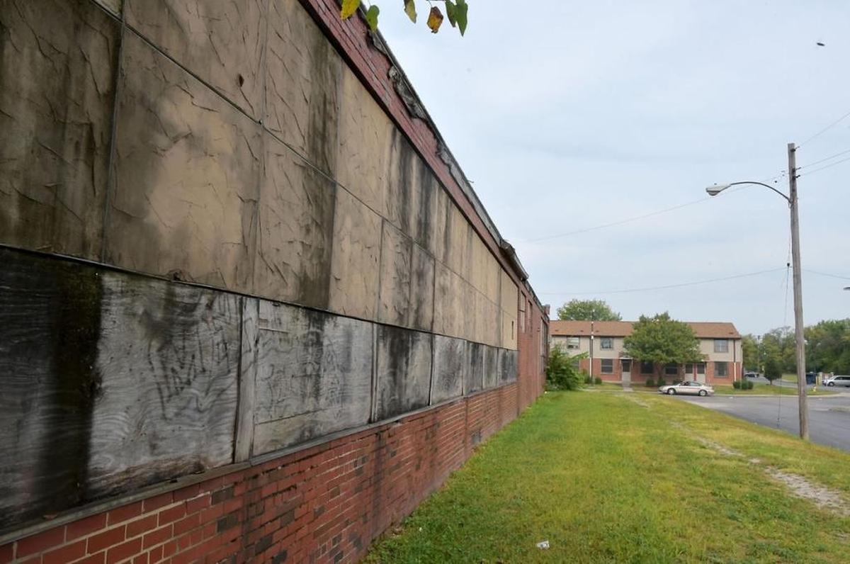 A boarded up school building sits in the foreground of the John DeShields Public Housing Complex.